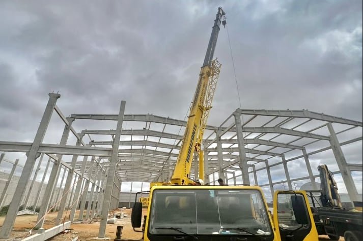 Estrutura industrial de grande porte em montagem, com guindaste da Novo Horizonte içando uma peça